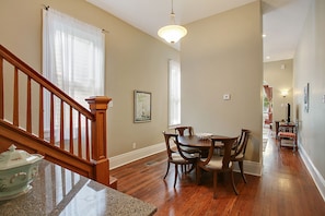 A dining area with a wooden table and chairs, a chandelier, and a staircase with wooden railings.