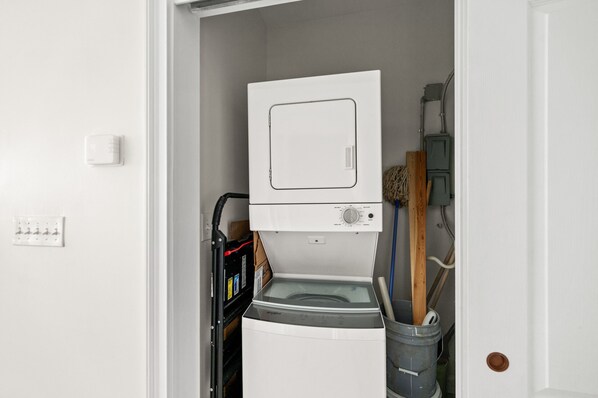 A compact laundry room with a front-loading washing machine, a dryer, and a utility sink.