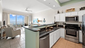 A modern kitchen with white cabinets, a stainless steel oven, and a black countertop. - Indies 704 | 3BR/2BA Penthouse Condo | Sleeps 9 | Gulf Views & Heated Pool (GULF SHORES)