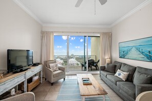 A living room with a TV, sofa, and a balcony with a view.