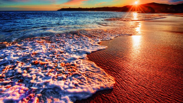 Una playa con olas al atardecer.
