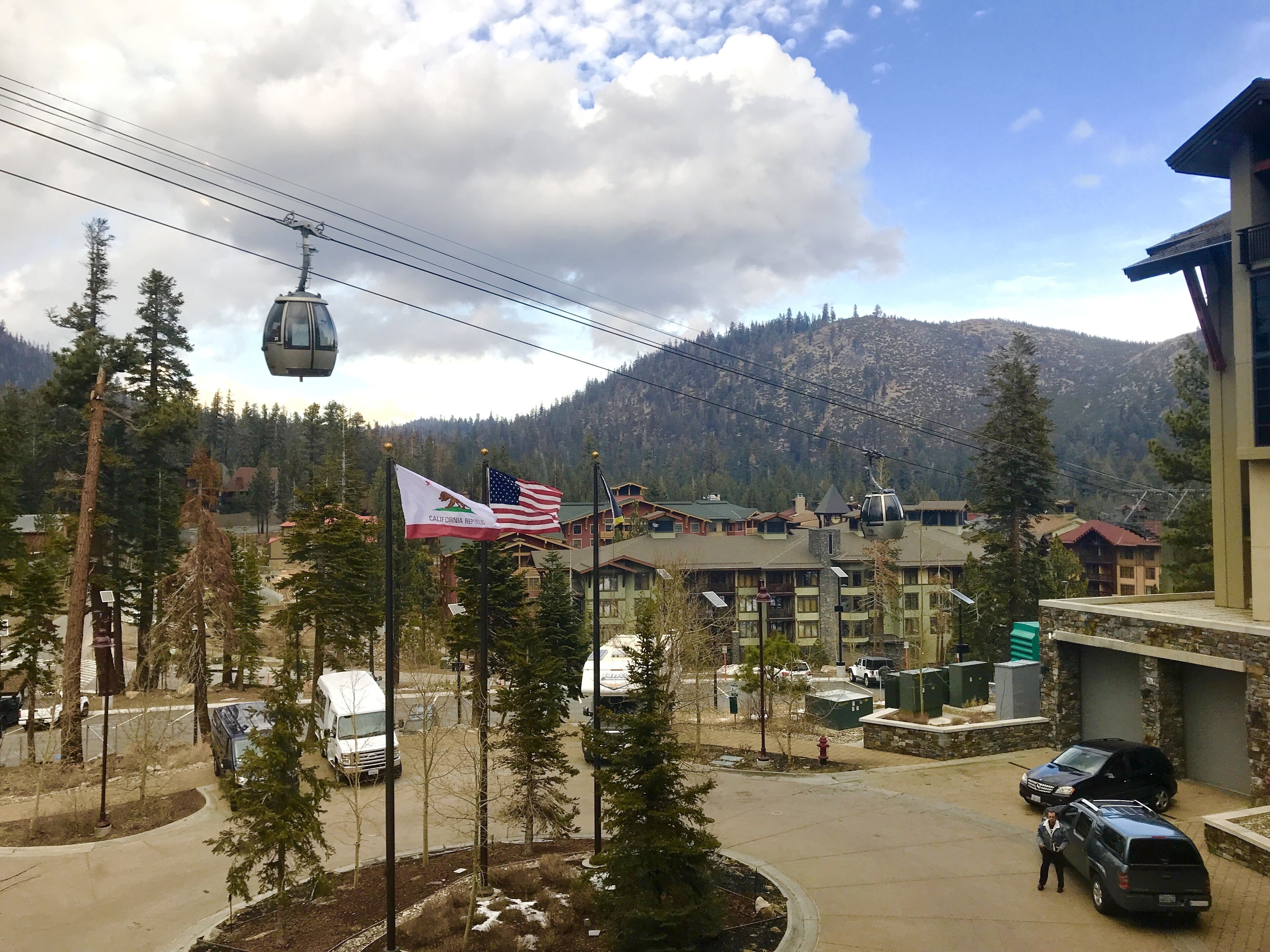 A mountainous area with a cable car, flags, and buildings.