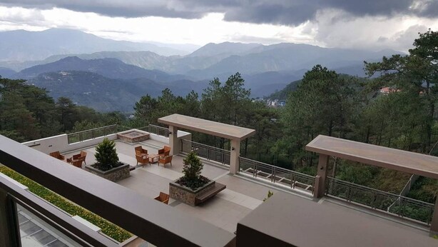 A rooftop terrace with outdoor furniture and planters, overlooking a mountainous landscape. - N603 Outlook Ridge Residences (Baguio)