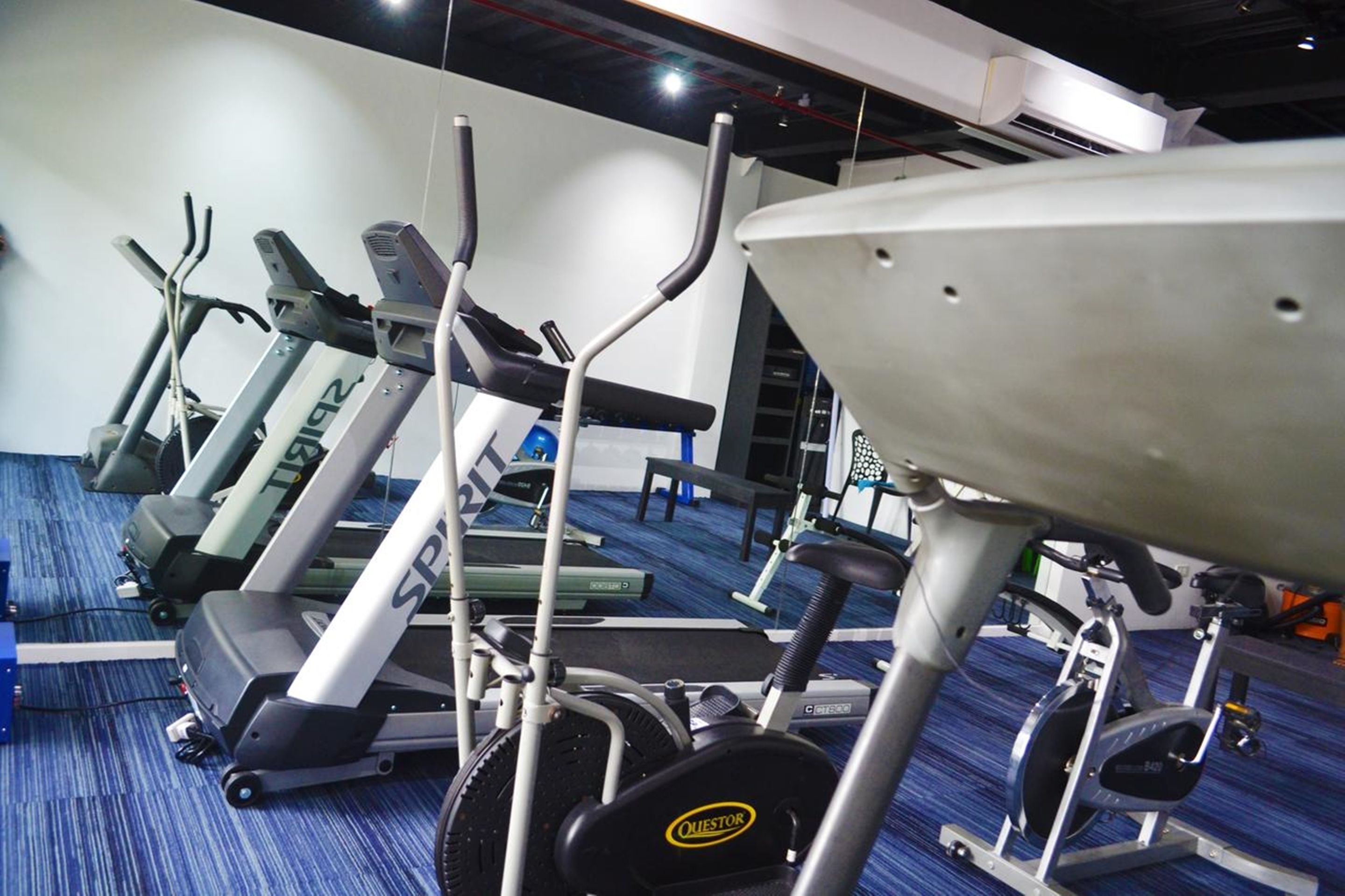 Een fitnessruimte met diverse loopbanden, elliptische trainers en een hometrainer.
