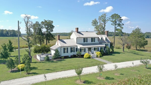 A large white house with a wrap-around porch, surrounded by a well-maintained lawn and trees. - Cedar Lane Plantation dated back to early 1809 (New Kent)