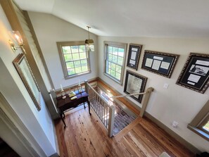 A staircase with wooden flooring, a railing, and a view of the outdoors through windows. - Cedar Lane Plantation | Historic Estate Retreat (New Kent)