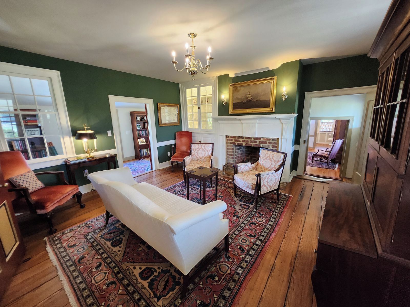 A traditional living room with a fireplace, a white sofa, and a patterned rug.