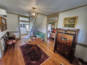 A spacious living room with a high ceiling, a wooden coffee table, a green sofa, and a traditional wooden cabinet. - Cedar Lane Plantation | Historic Estate Retreat (New Kent)