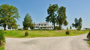 A two-story house with a front porch, surrounded by a grassy lawn and trees. - Cedar Lane Plantation dated back to early 1809 (New Kent)
