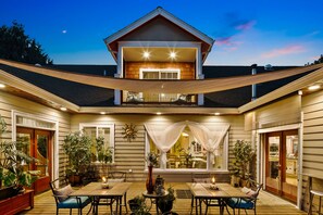 A two-story house with a covered patio area, outdoor seating, and various potted plants. - Grayson B&B — ADA Garden & Patio Suite — By Evergreen Equestrian (Monroe)