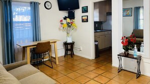 A living room with a dining table, a sofa, a TV, and a kitchen in the background. - 2 Bed 1 Bath  , Grand Pa's Cottage, Long Term Vacation Rentals . (Santa Barbara)