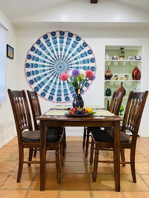Enjoy meals in this cozy dining area with a round table for four, surrounded by comfortable chairs and a beautiful wall hanging.