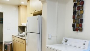 A kitchen with a refrigerator, washing machine, and a trash can. - 2 Bed 1 Bath  , Grand Pa's Cottage, Long Term Vacation Rentals . (Santa Barbara)