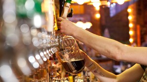 A bartender pouring drinks into glasses.