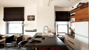 A compact kitchen with a central island, a dining area with a chair, and a window with a view.