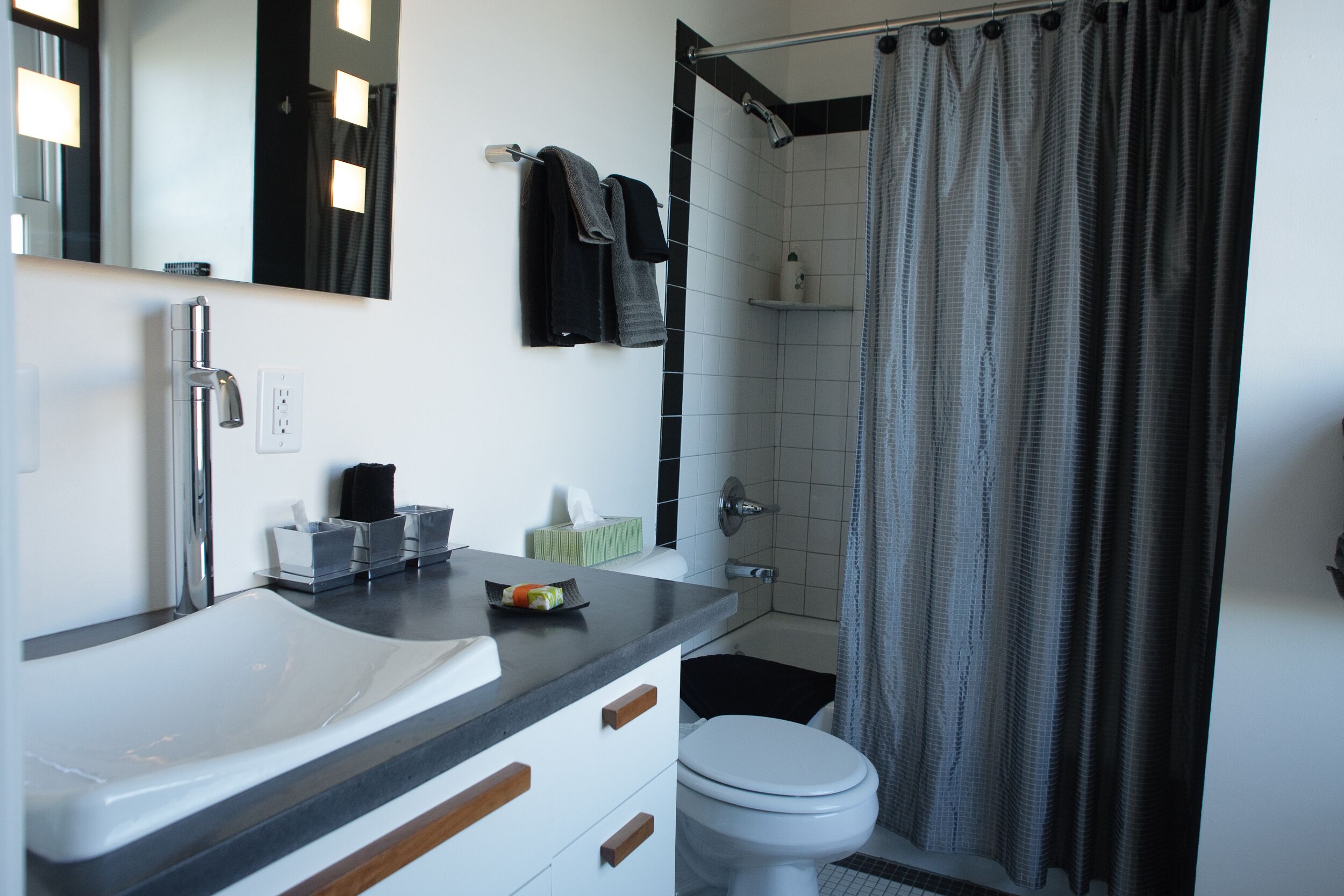 A modern bathroom with a white sink, a mirror, a toilet, and a shower curtain.