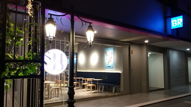 Exterior de un restaurante con terraza, un letrero de neón y un diseño moderno.