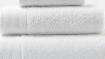 Three neatly folded white towels stacked on top of each other.