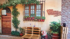 Fachada rústica de un edificio con puerta de madera, ventana con reja de metal y un letrero que dice "Vin-Cottage".