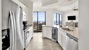 Une cuisine moderne équipée d’appareils électroménagers en acier inoxydable, d’un lave-vaisselle et d’une grande fenêtre donnant sur un balcon.
