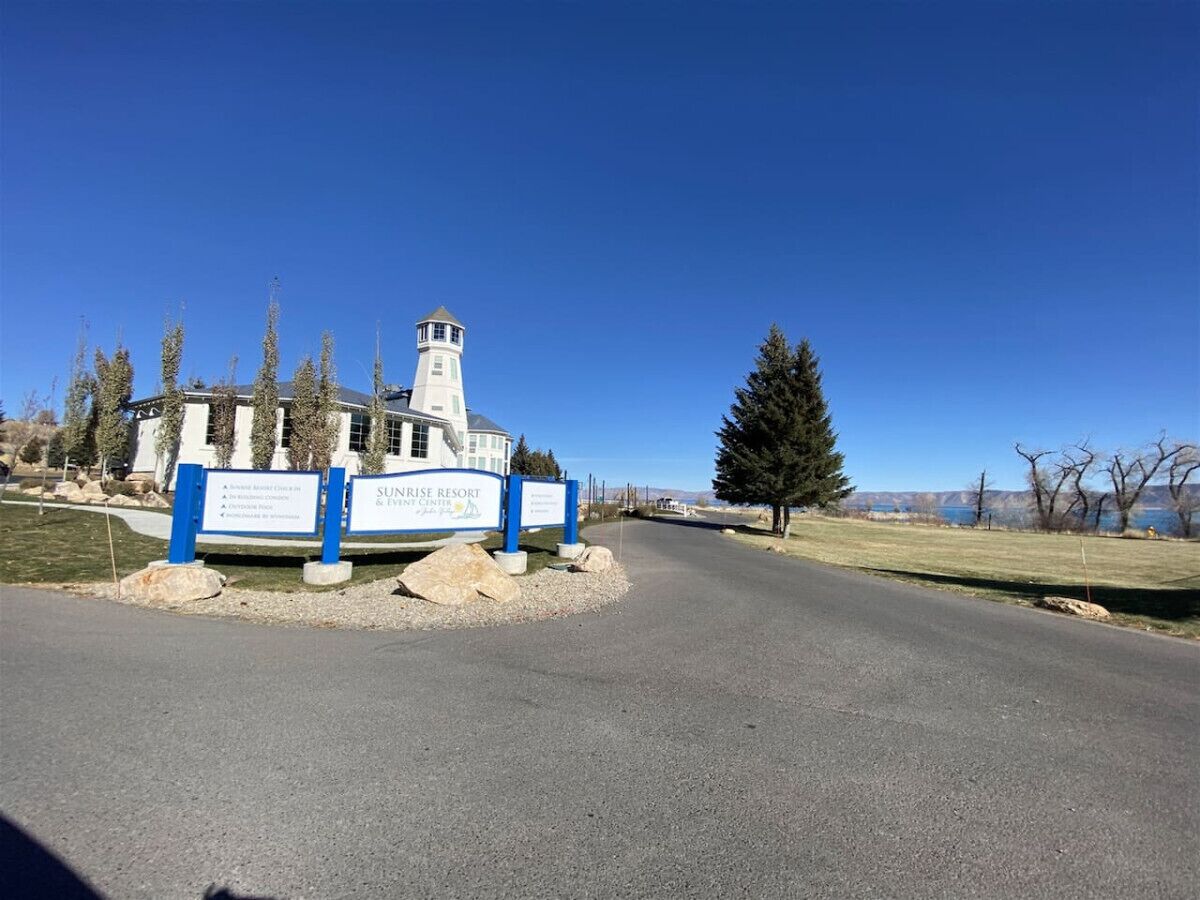 Une enseigne indiquant l’emplacement du Sunrise Resort & Event Center, avec un ciel dégagé et une route menant au bâtiment.