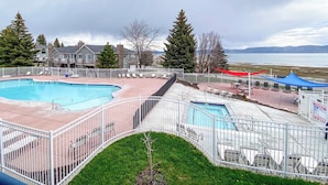 A pool area with a fenced deck, lounge chairs, and a view of a lake and mountains. - Beautiful Inn Building Condo #208 Pet friendly (Garden City)