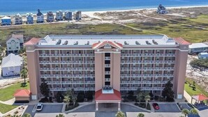 Un hotel grande con varios pisos, un patio central y vistas a la playa y al océano.