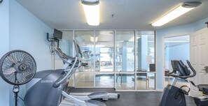 Een sportschool met loopbanden, een hometrainer en een ventilator.