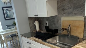 A modern kitchen with white cabinets, a wooden countertop, and a stainless steel sink. - Completely remodeled beautiful waterfront property on canal with dock (Port Charlotte)