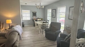 A spacious living room with a sofa, armchair, and a dining area with a table and chairs. - Completely remodeled beautiful waterfront property on canal with dock (Port Charlotte)