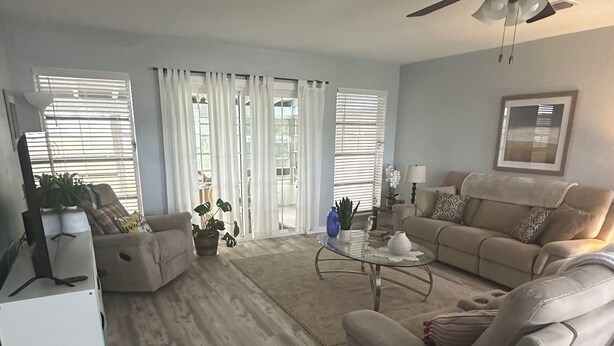 A spacious living room with a beige sofa, a glass coffee table, and a ceiling fan. - Completely remodeled beautiful waterfront property on canal with dock (Port Charlotte)