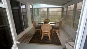 A covered patio area with a dining table and chairs, large windows, and a ceiling fan. - Completely remodeled beautiful waterfront property on canal with dock (Port Charlotte)