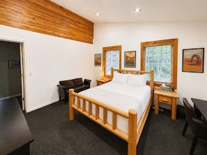 Une chambre à coucher avec un lit en bois, un bureau, une chaise et un canapé.