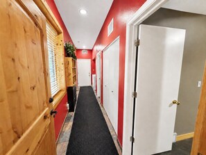 Un couloir avec des portes en bois, une moquette noire et des murs rouges.