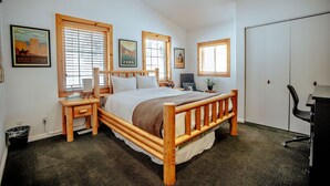A bedroom with a wooden bed, two bedside tables, a desk, and a wardrobe.