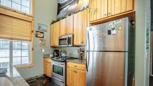 A kitchen with wooden cabinets, a stainless steel refrigerator, a microwave, and a stove.
