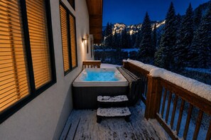 A hot tub on a wooden deck with snow-covered railings, overlooking a snowy mountain landscape. - Great Western by Cottonwood Lodging (Brighton)