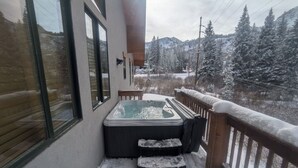 A hot tub on a balcony with a snowy landscape view.