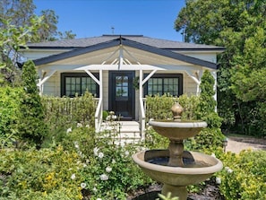 A house with a porch, a fountain, and a garden.