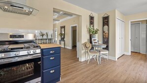 A kitchen with a stainless steel range, a blue cabinet, and a dining area with a table and chairs.