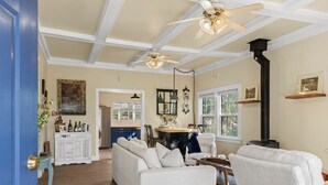 A spacious living room with a white sofa, a dining area with a wooden table, and a kitchen in the background.