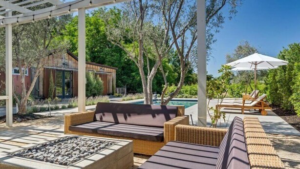 A covered outdoor seating area with a pool, wicker furniture, and a pergola.