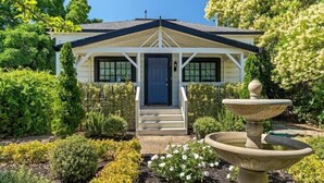 A house with a porch, a front door, and a garden with a fountain.