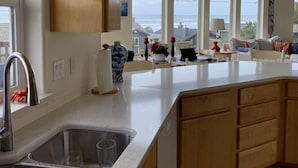 Cozinha com uma ilha grande, pia embutida e vista para o mar através de janelas amplas.
