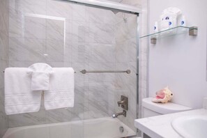Een bad/douchecombinatie, een haardroger, handdoeken, zeep