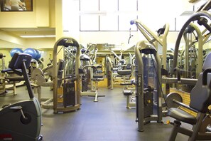 Una palestra con diverse macchine per esercizi, uno specchio a parete e palle da ginnastica sullo sfondo.