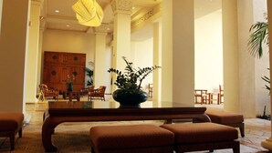 Eine geräumige Lobby mit einer großen Holzbank, einer zentral platzierten Pflanze und einer modernen Leuchte.