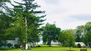A grassy yard with a flagpole, a wooden chair, and a bench.