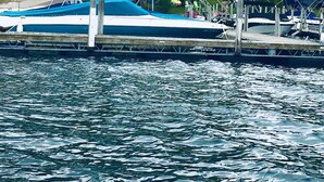 A dock with a sign for Cape Cod Village Club. Boats are moored at the dock.