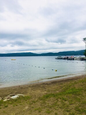 Une vue sur le lac, avec un quai, des eaux calmes et des collines à l’horizon.
